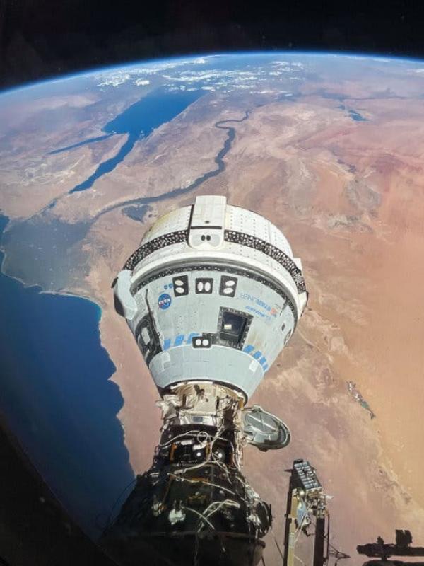 The conical gray shape of the Boeing Starliner spacecraft with its white “trunk” at the top looming over Egypt.