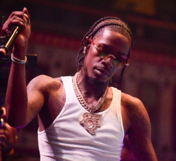 A man wearing a white T-shirt, sunglasses and a chunky necklace.