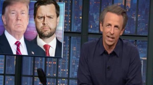 The faces of Donald Trump and JD Vance are on a screen beside him. Seth Meyers sits behind a desk with a background of a cityscape at night.