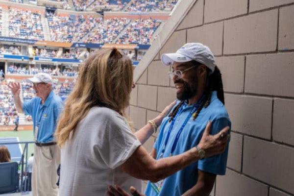 A woman embraces an usher in a blue shirt at an entryway.