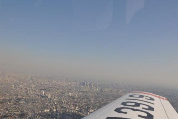 The wing of an airplane with bold lettering on it over a cityscape.