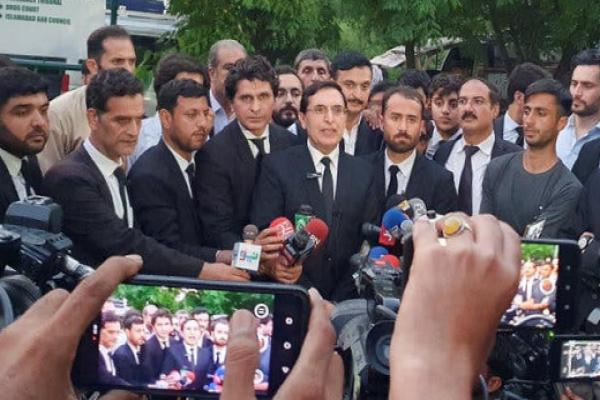 A group of men in dark suits facing a scrum of reporters holding up microphones and cell phones.