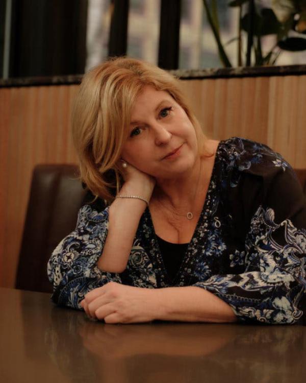 Liane Moriarty poses for a portrait, sitting down, looking straight at the camera.