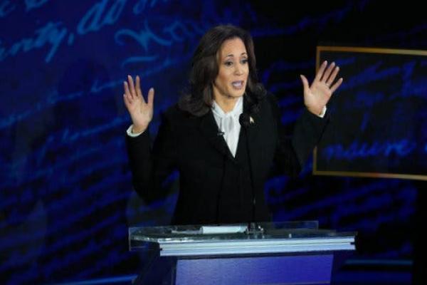 Kamala Harris behind a lectern holding her hands in the air.